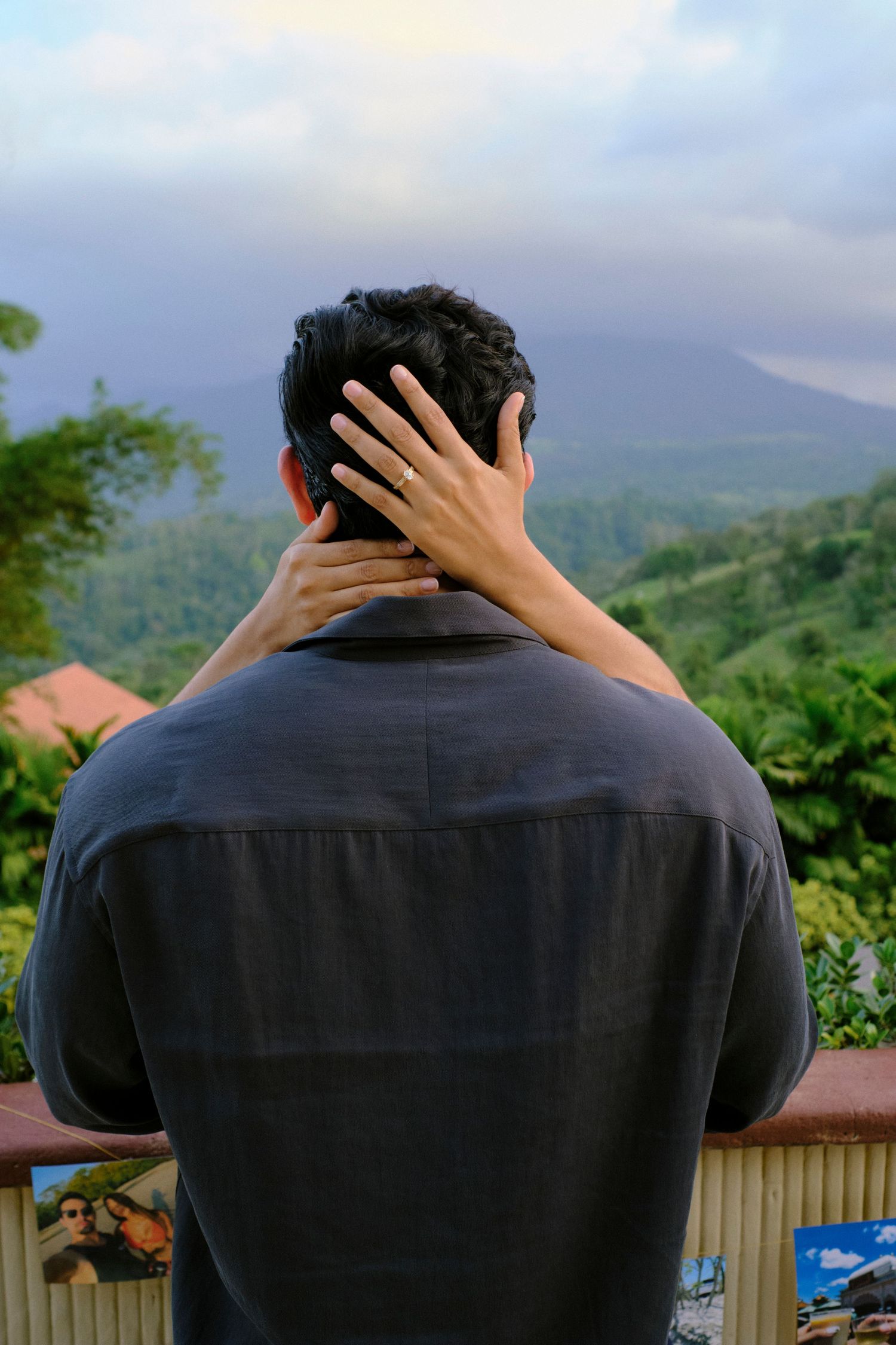 Man standing at scenic overlook with mountain views as woman places hand affectionately on his neck.