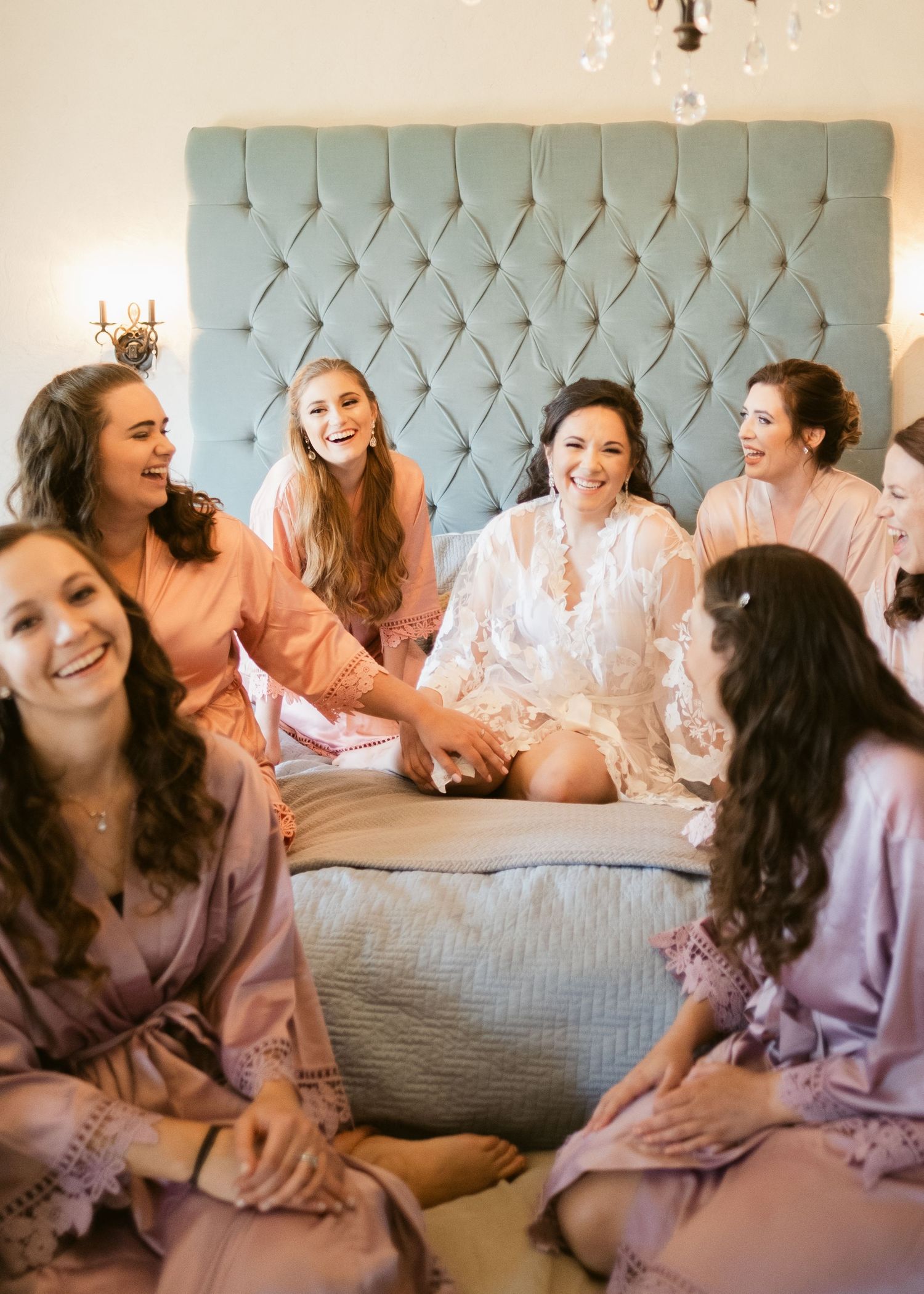 Bride and bridesmaids sitting on a bed at Chateau Selah wedding in Tennessee.
