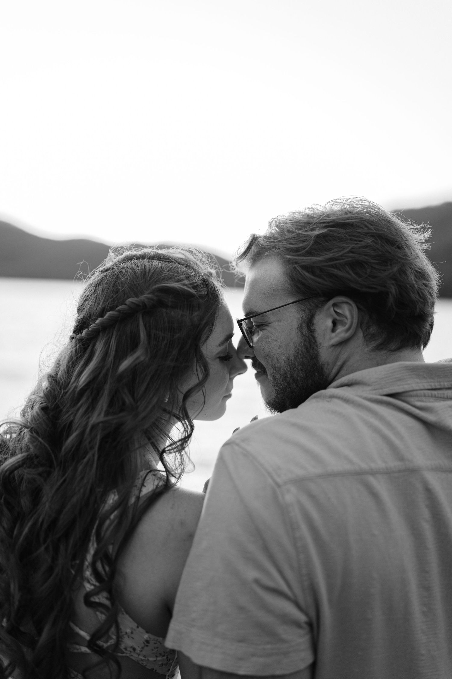 Black and white close-up of a couple sharing an intimate moment by a lake.