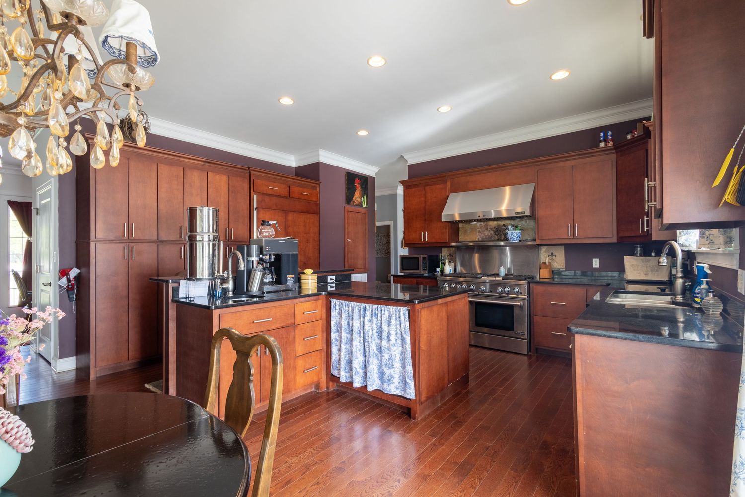 Elegant kitchen with rich cherry wood cabinets, black granite countertops, and stainless steel appliances.