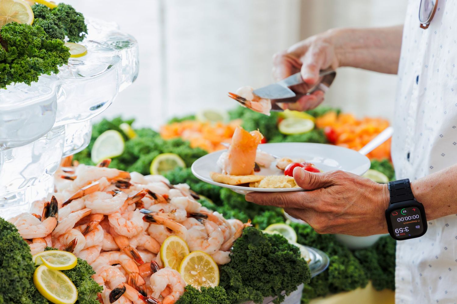 Chef serving shrimp at an elegant seafood buffet with ice sculpture and vegetables.