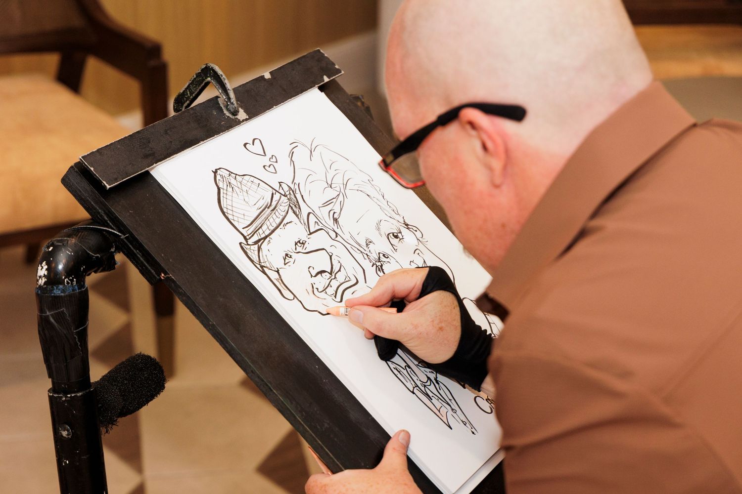 Artist drawing a caricature sketch on a clipboard easel at an event.