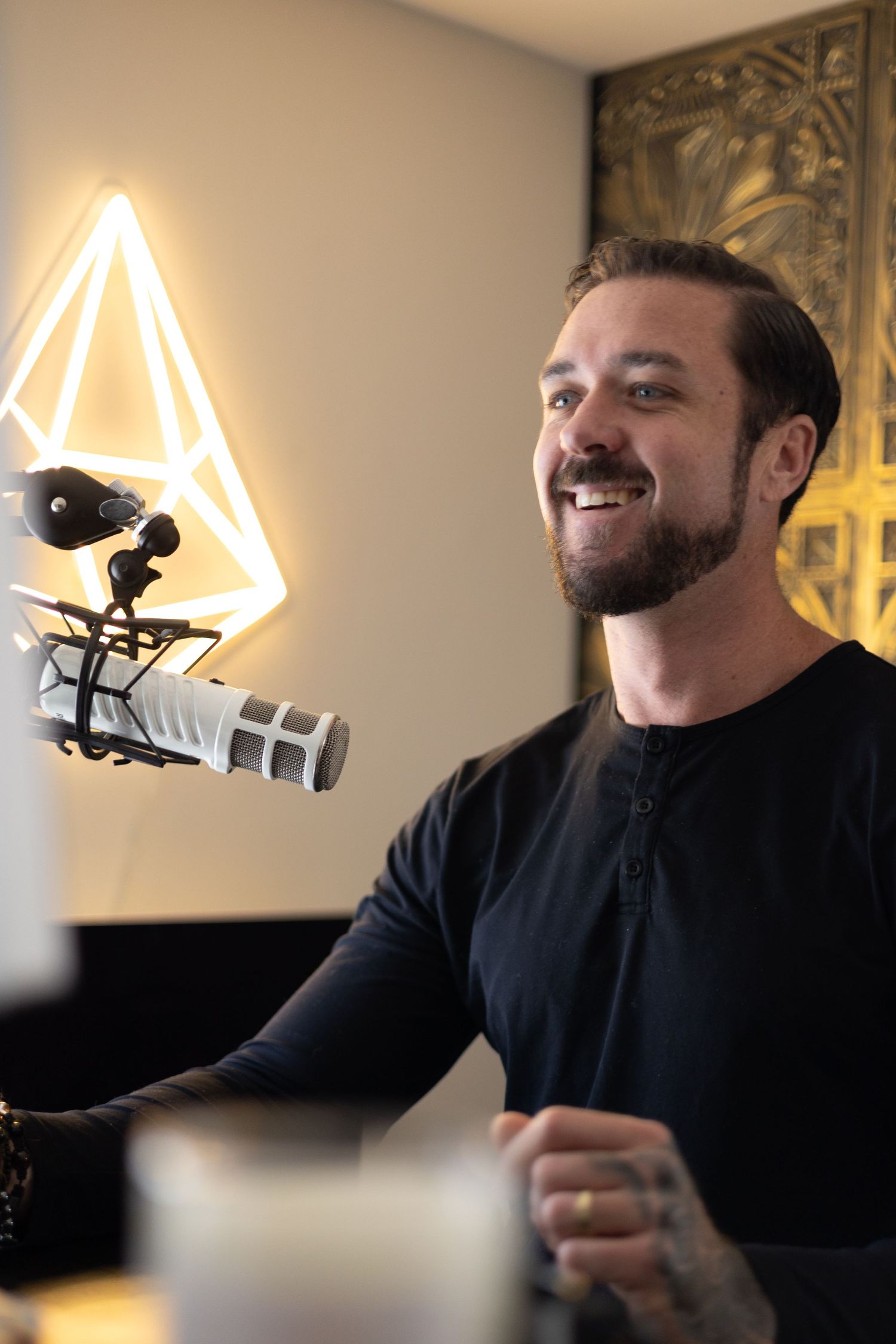 Smiling bearded man recording podcast with professional microphone.