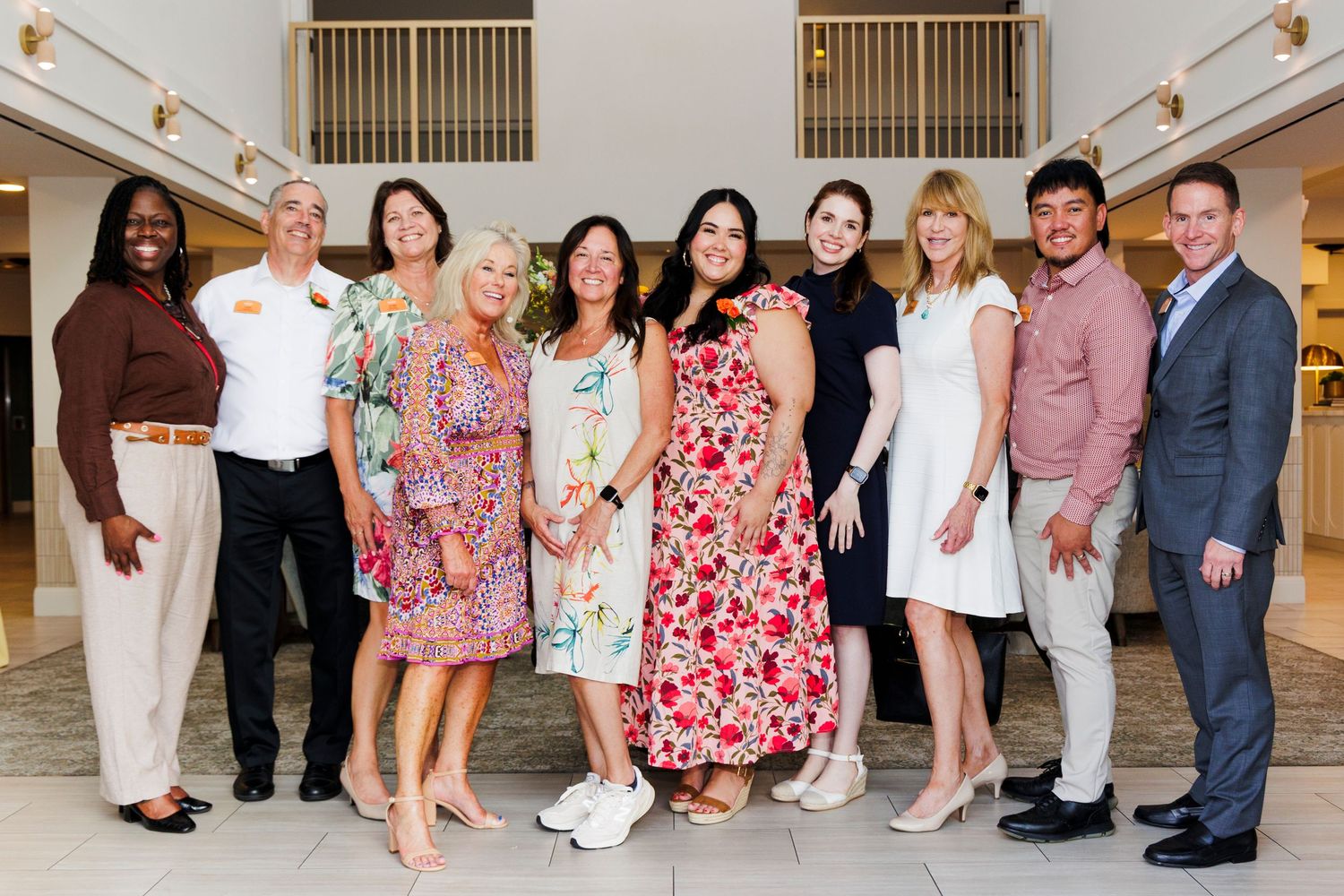 Group of ten smiling professionals posing together indoors at a corporate event.