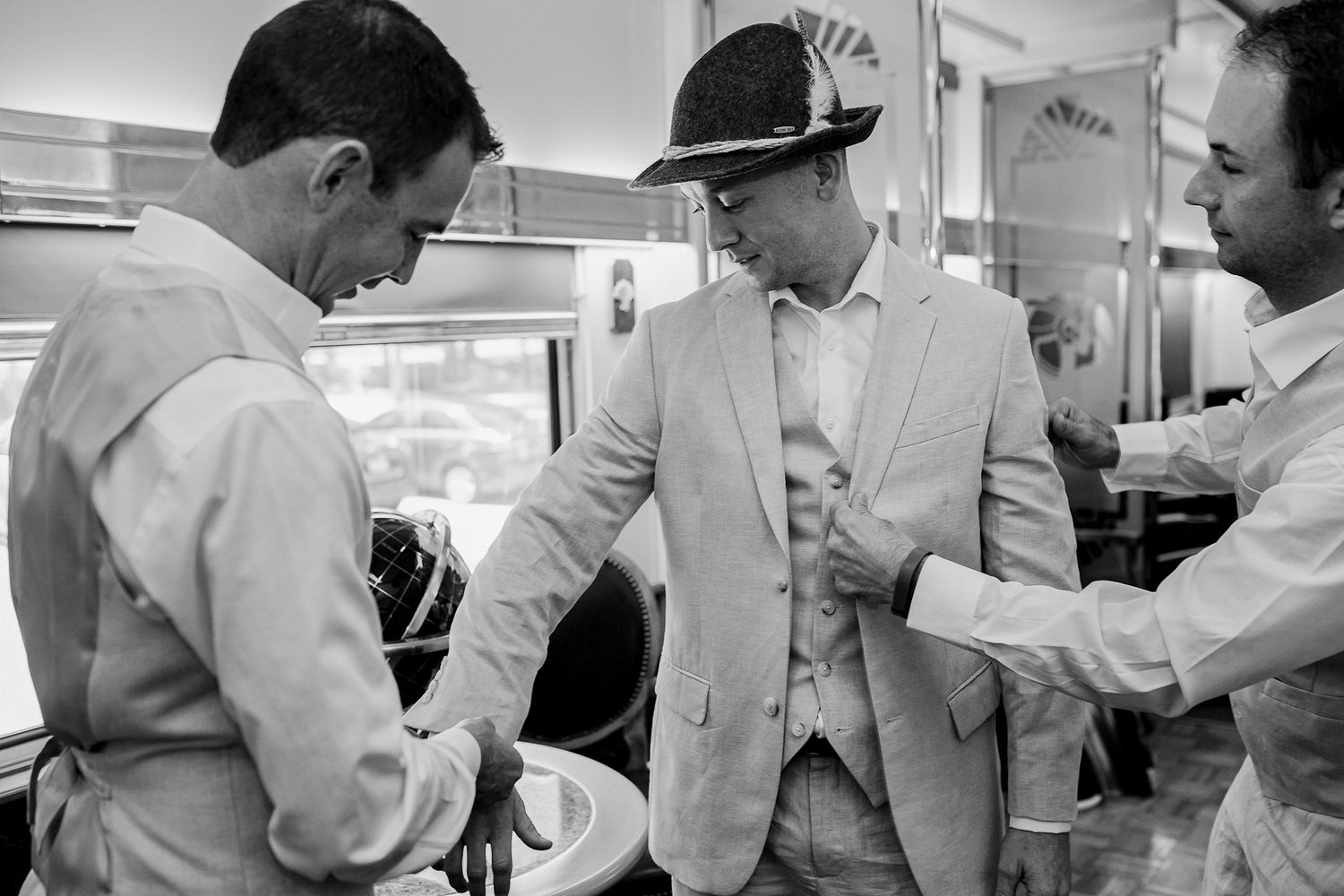 Vintage black and white photo of men getting fitted for formal attire.