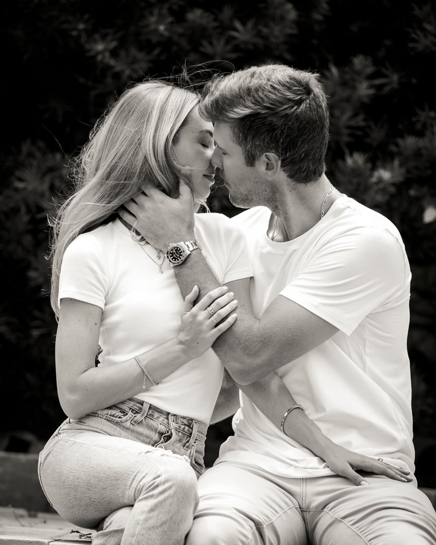 Intimate black and white portrait of couple sharing tender moment outdoors.