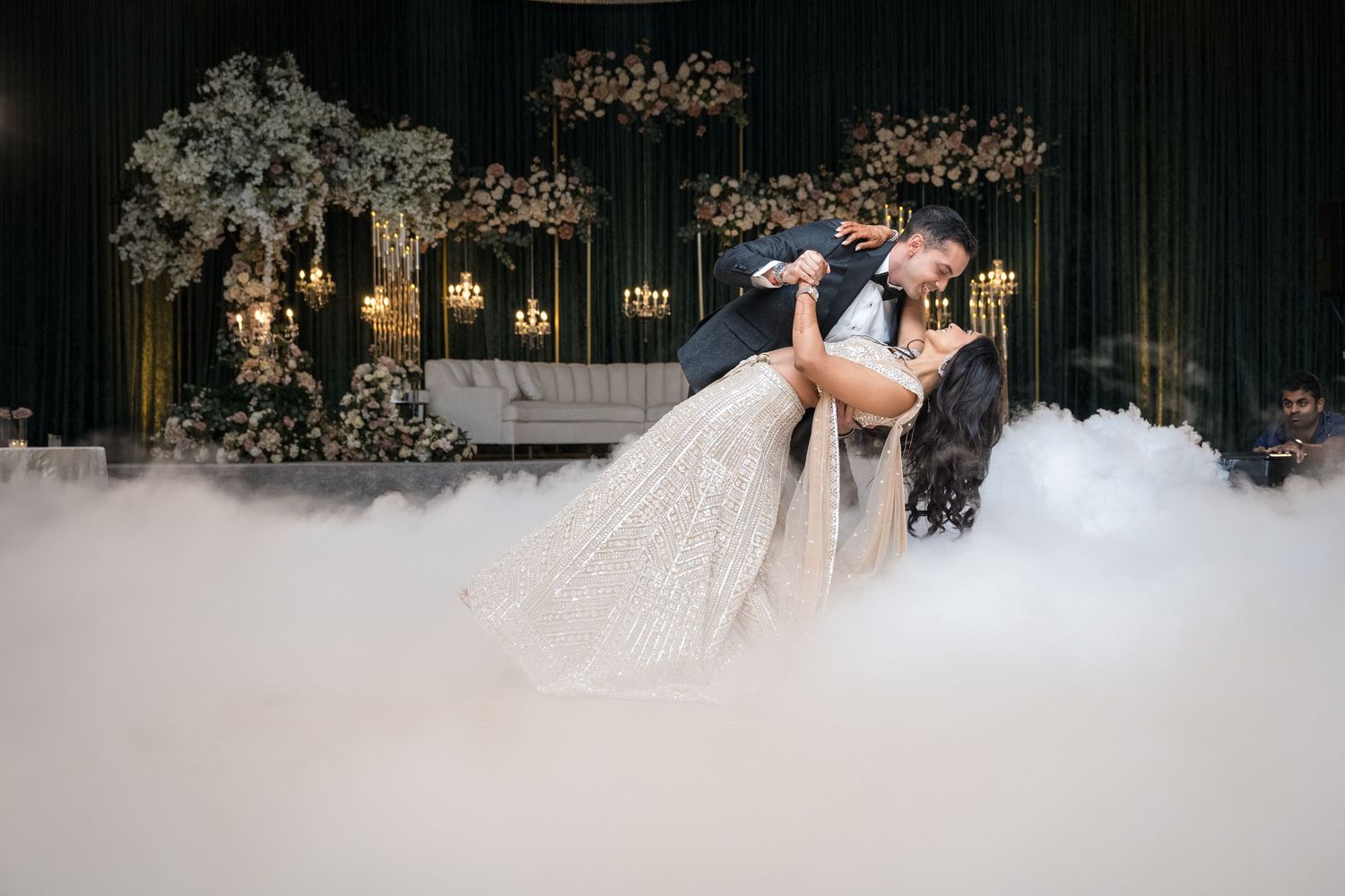 Dramatic wedding dance dip with fog effect and floral arch backdrop.