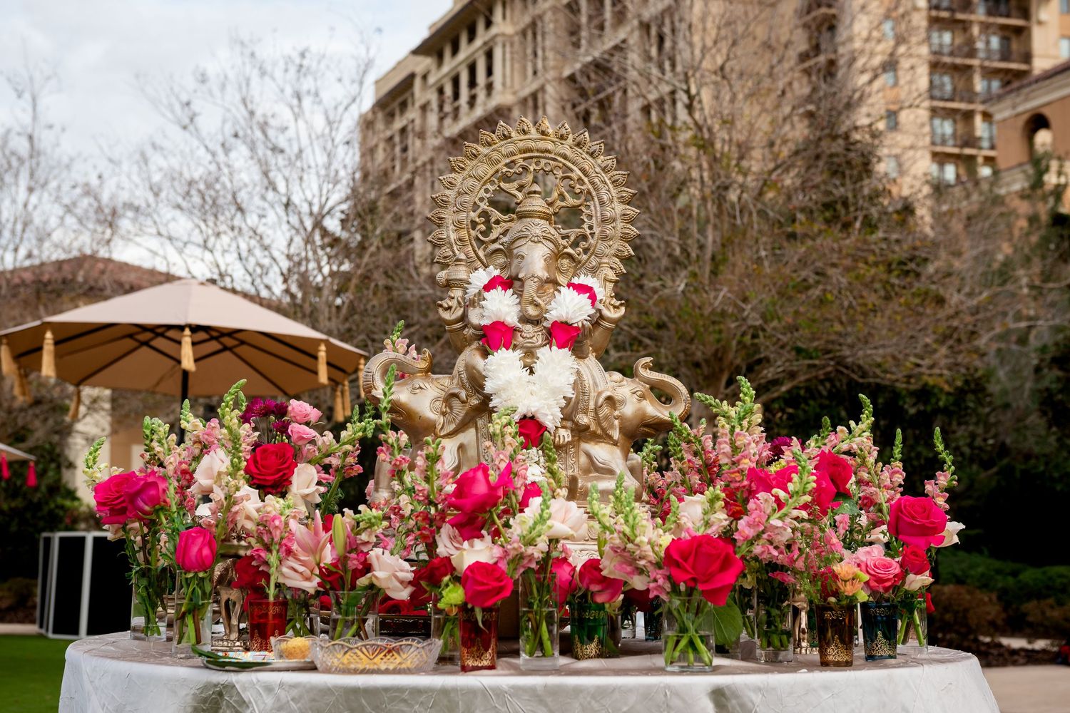Luxurious wedding centerpiece with red roses and gold decor on an ornate table setting.