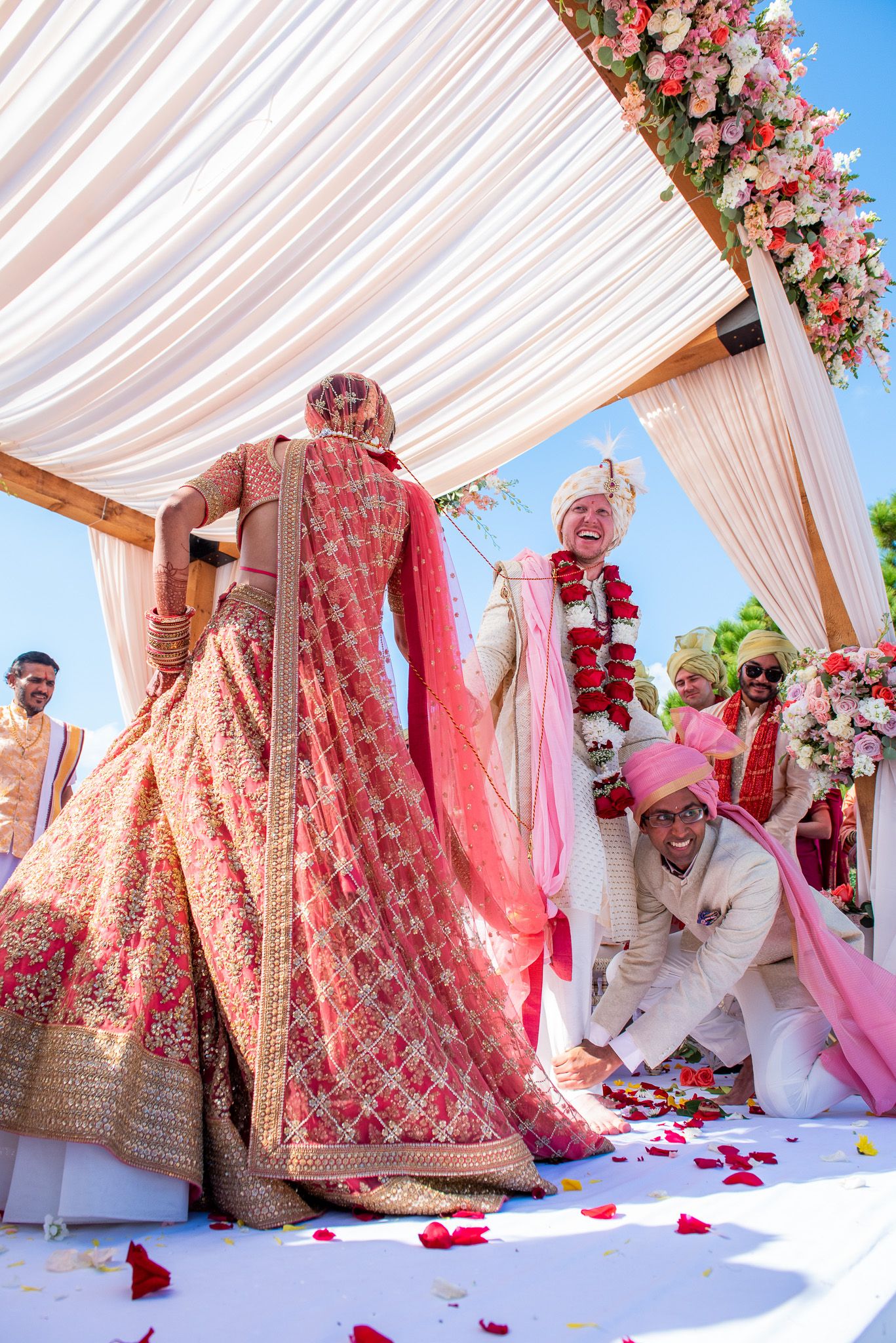 Wedding ceremony under draped white canopy decorated with pink flowers.