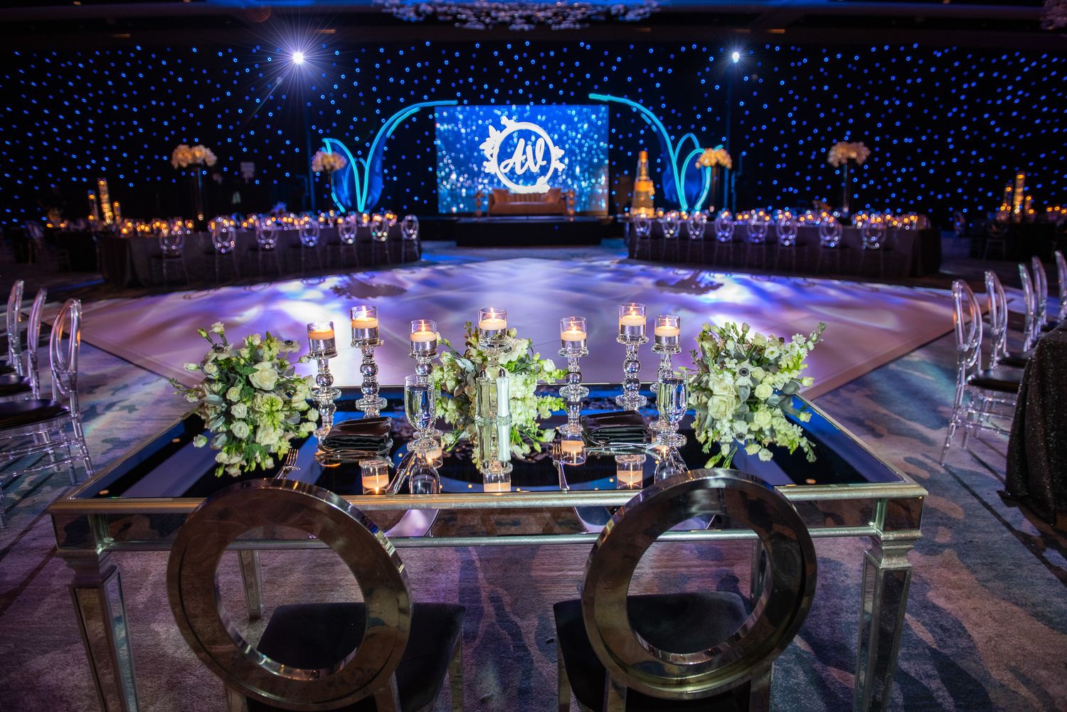 Elegant reception venue with starlit backdrop, floral centerpieces and modern furniture setup.