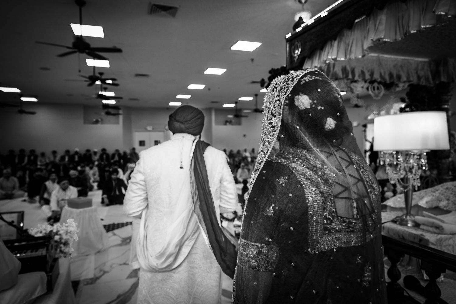 Black and white candid shot of couple in traditional South Asian wedding attire.