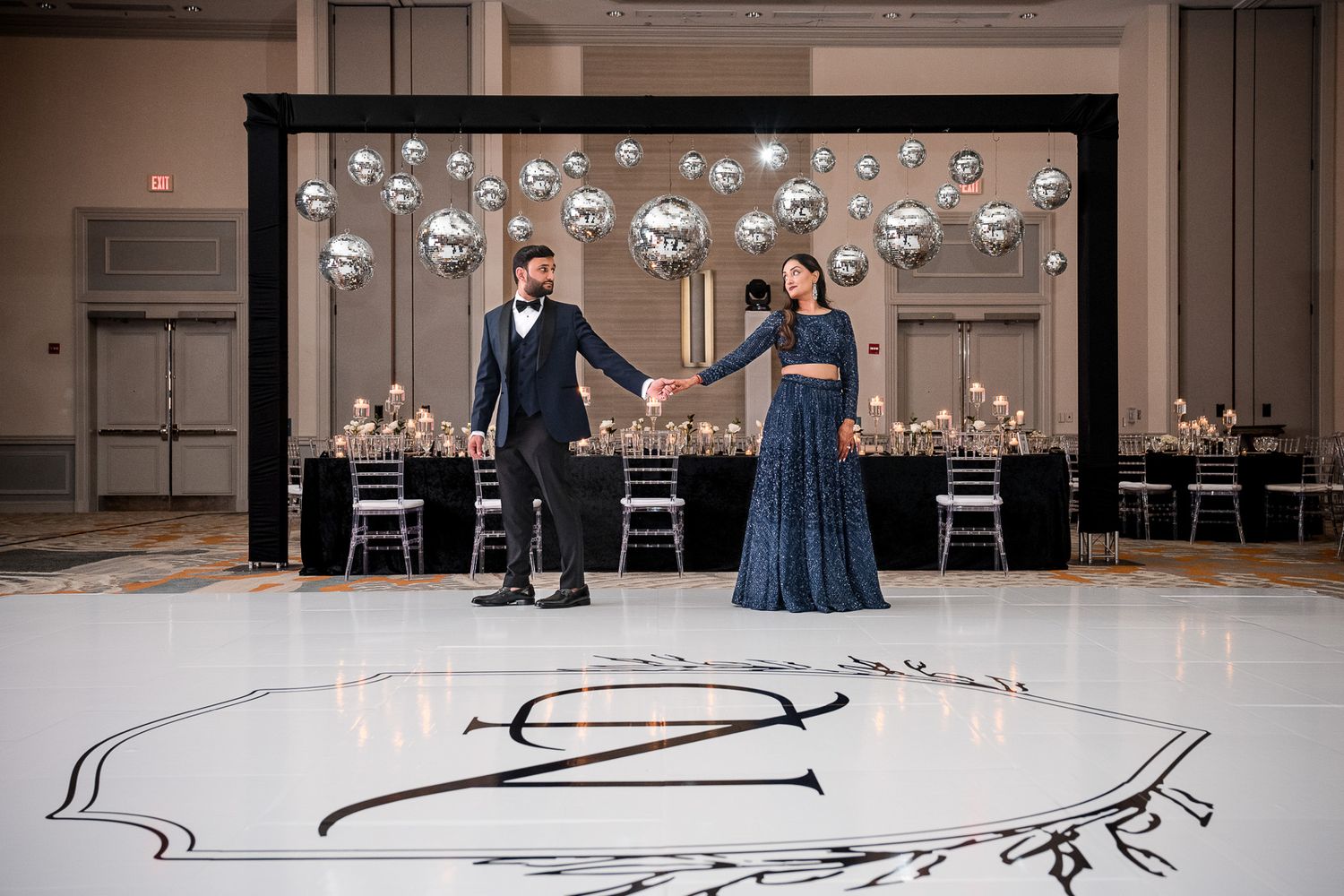 Glamorous ballroom setup with hanging disco balls and monogrammed dance floor for an elegant reception.