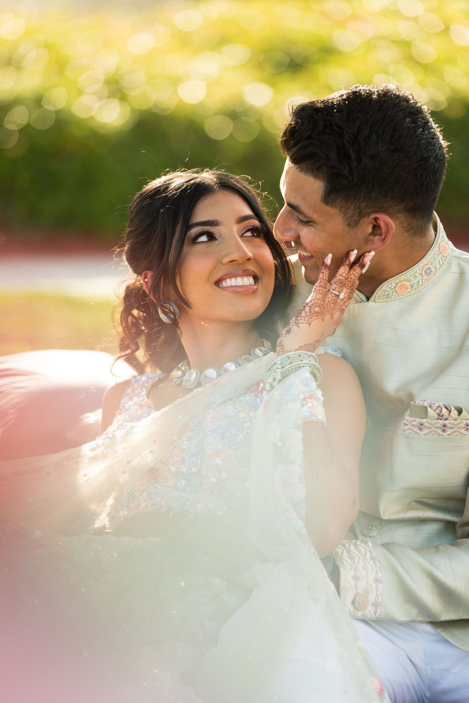 Romantic golden hour portrait of newlyweds in traditional attire sharing an intimate moment.