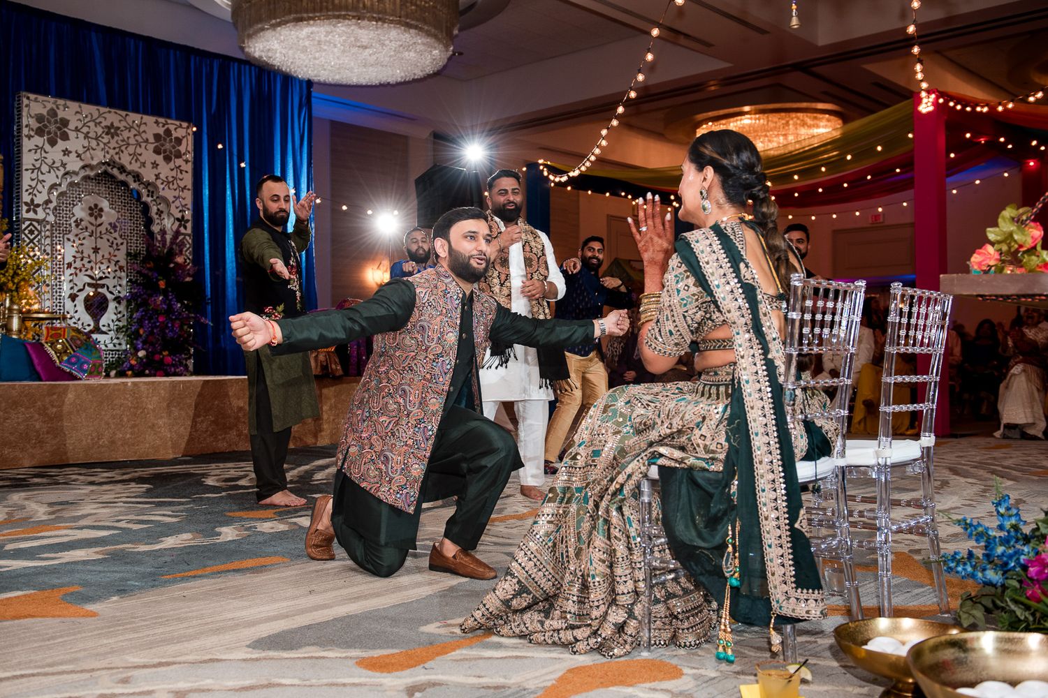 Wedding party performing choreographed dance routine at reception with decorative lighting.