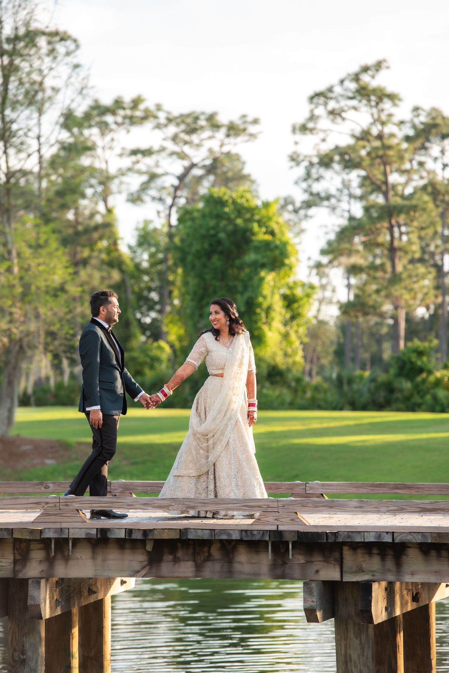 Couple stands on wooden dock over lake in romantic wedding photo.
