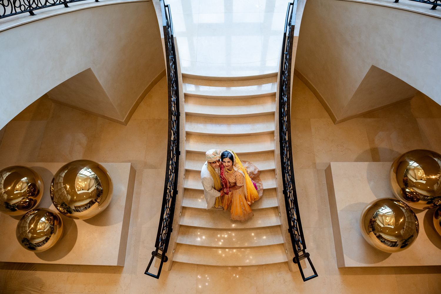 Elegant bridal portrait on grand staircase with golden sphere decorations.
