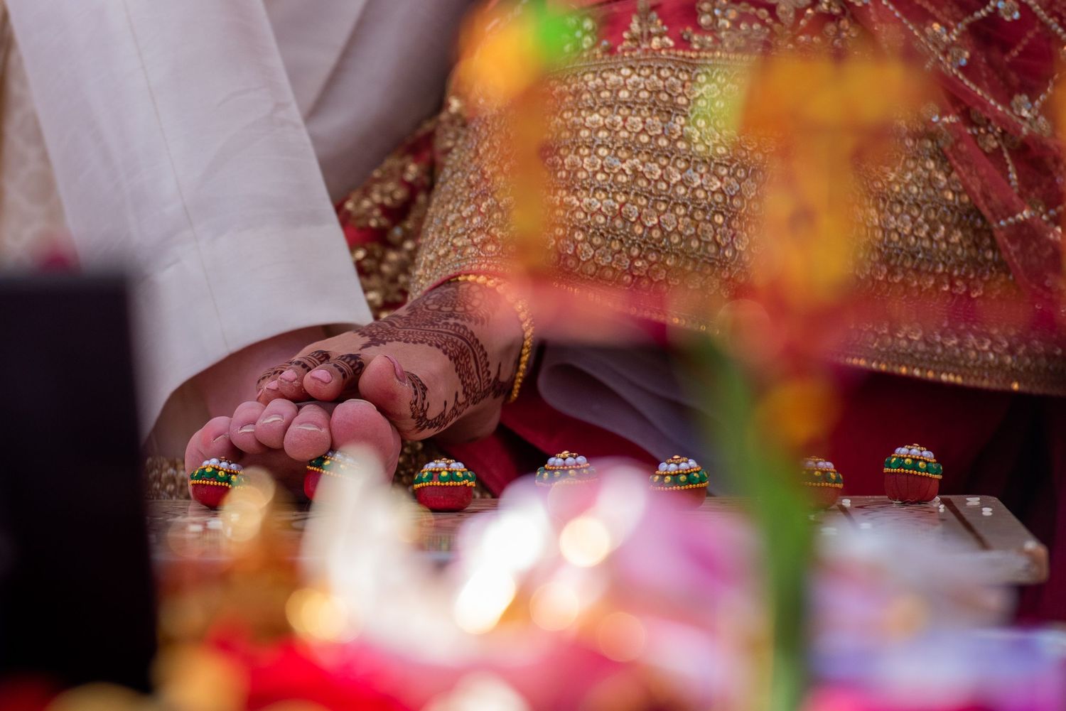 Detailed view of hands adorned with henna and jewelry during traditional ceremony ritual.