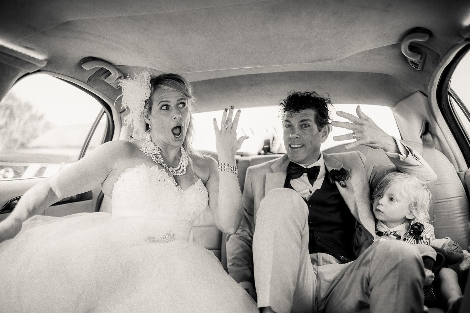 Candid moment of newlyweds reacting with surprise in car backseat.