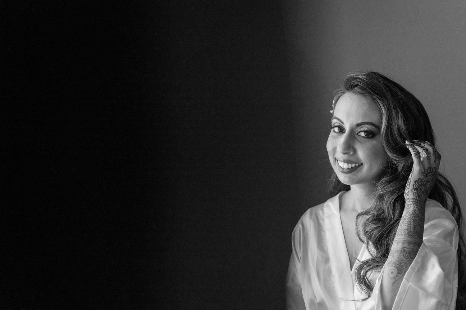 Black and white portrait of woman in robe getting ready with elegant hairstyling.