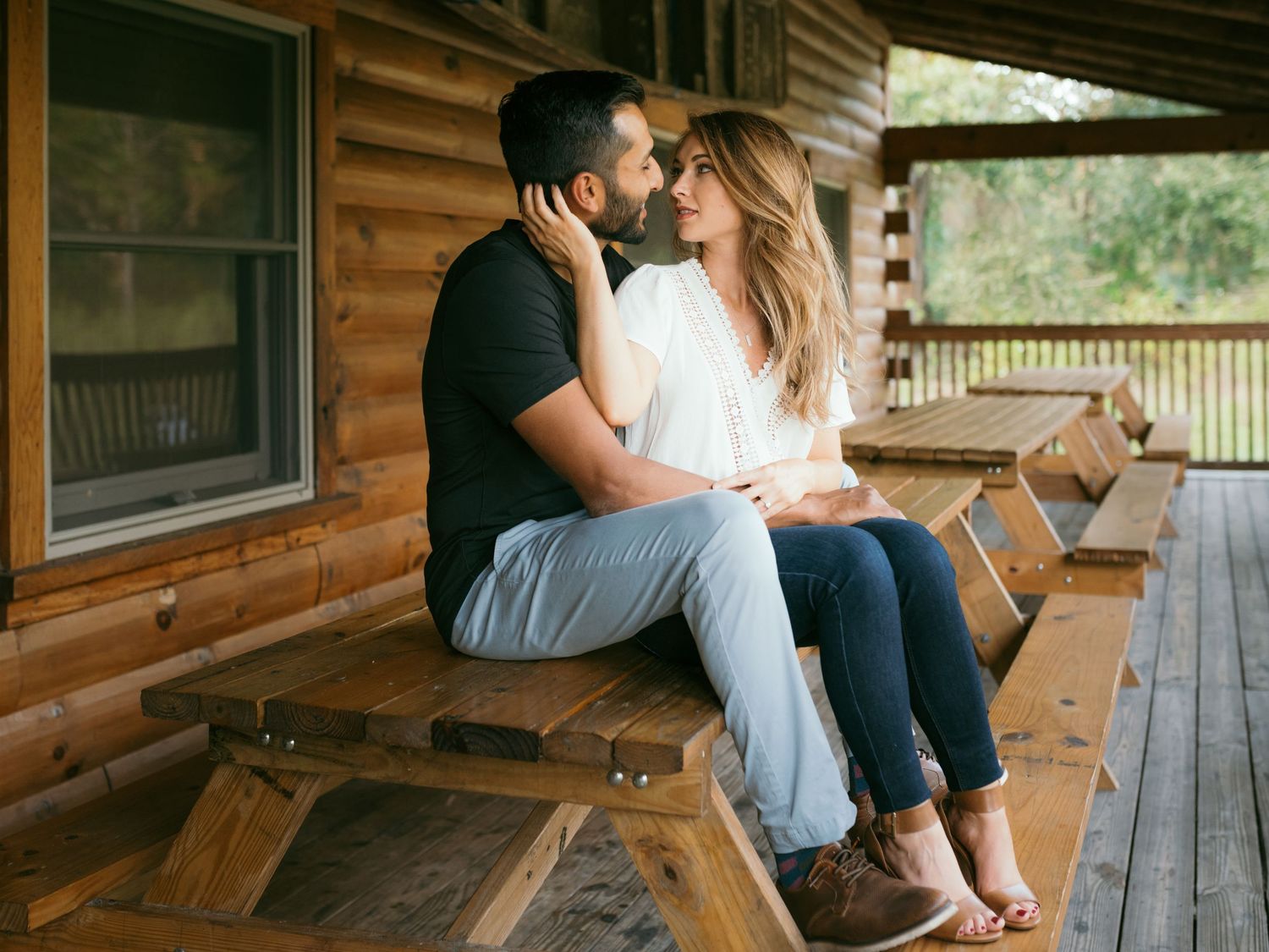 Romantic couple sharing an intimate moment on a rustic wooden picnic table.