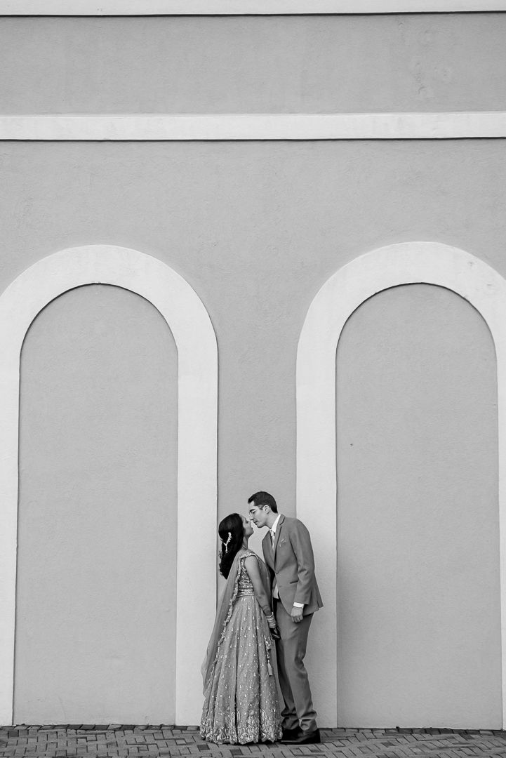 Black and white romantic moment of a couple sharing an intimate moment in an arched architectural setting.