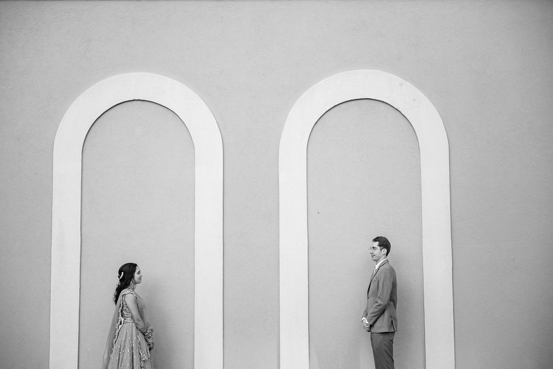 Minimalist black and white portrait of a couple posing in separate arched alcoves.