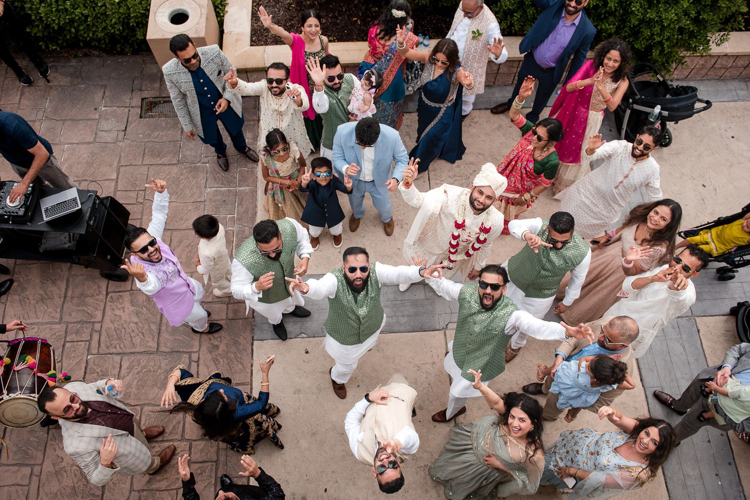 Aerial view of wedding guests gathered on a brick patio during an outdoor celebration ceremony.