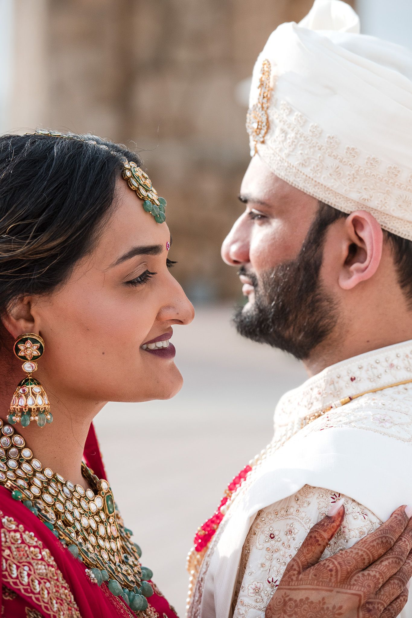 Close-up portrait of couple in traditional Indian wedding attire sharing intimate moment.