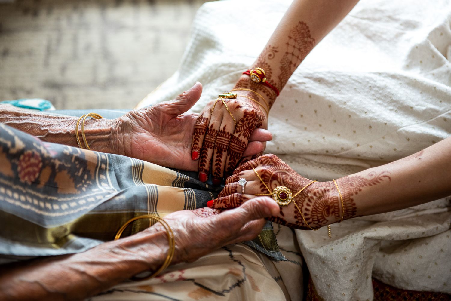 Intricate henna designs being applied to hands during a traditional Indian wedding ceremony preparation.