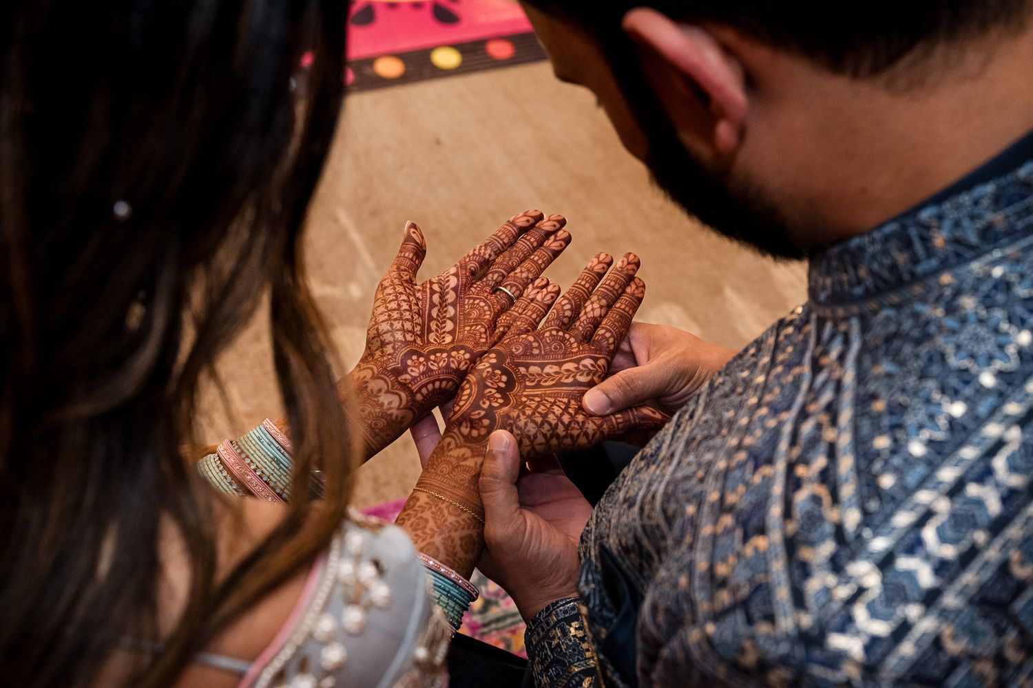 Close-up shot of hands displaying detailed mehndi patterns during traditional ceremony.