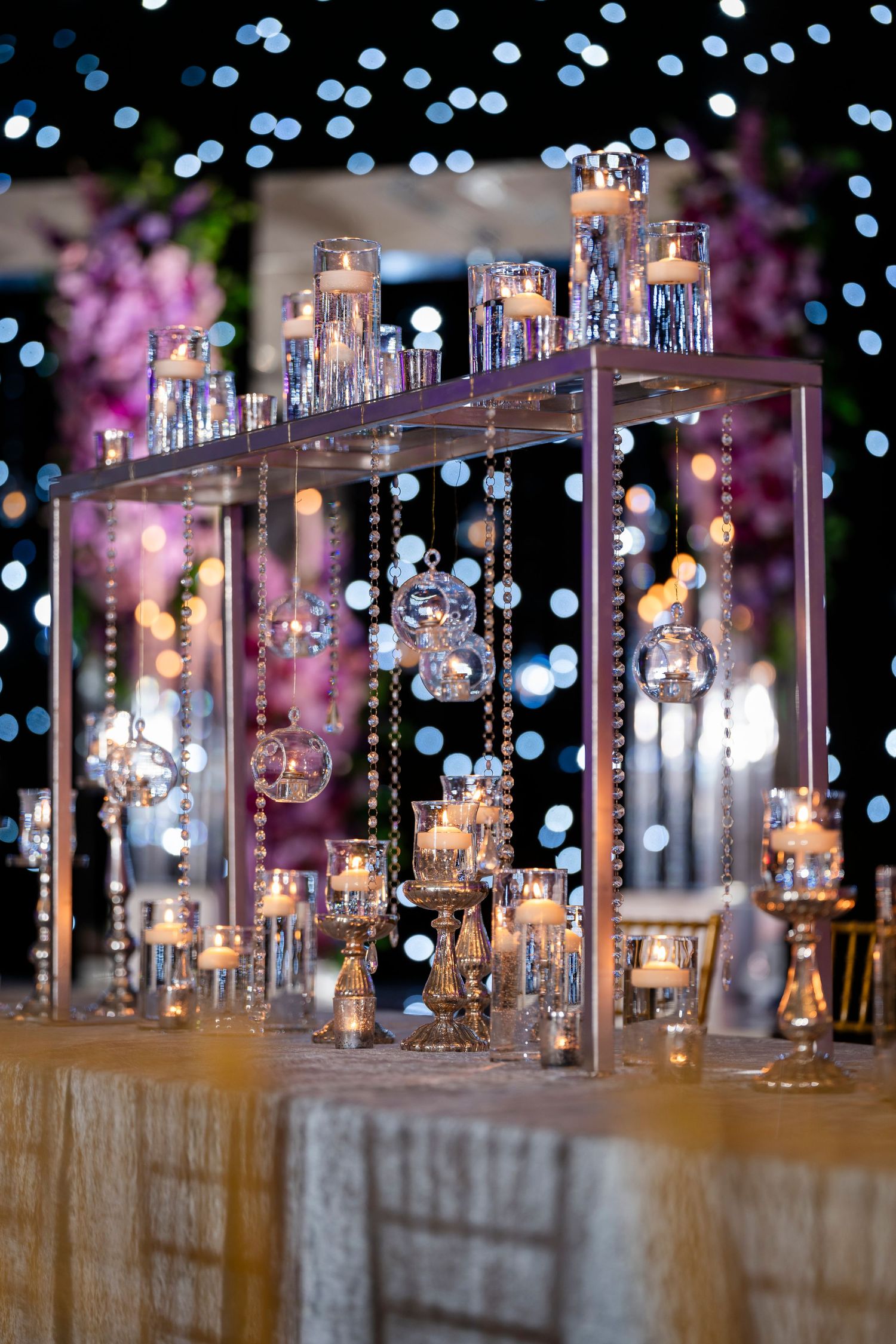 Elegant wedding decor featuring tiered candle holders with blue bokeh lighting.