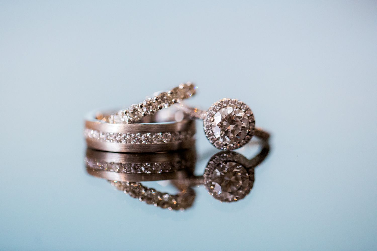 Rose gold wedding rings with diamonds captured in artistic reflection.