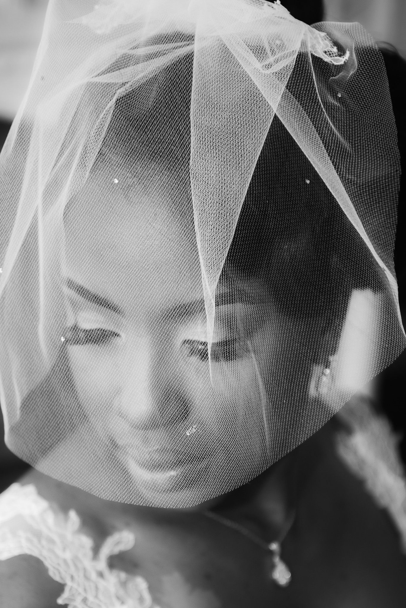 Close-up black and white portrait of a bride wearing a delicate veil with soft lighting.