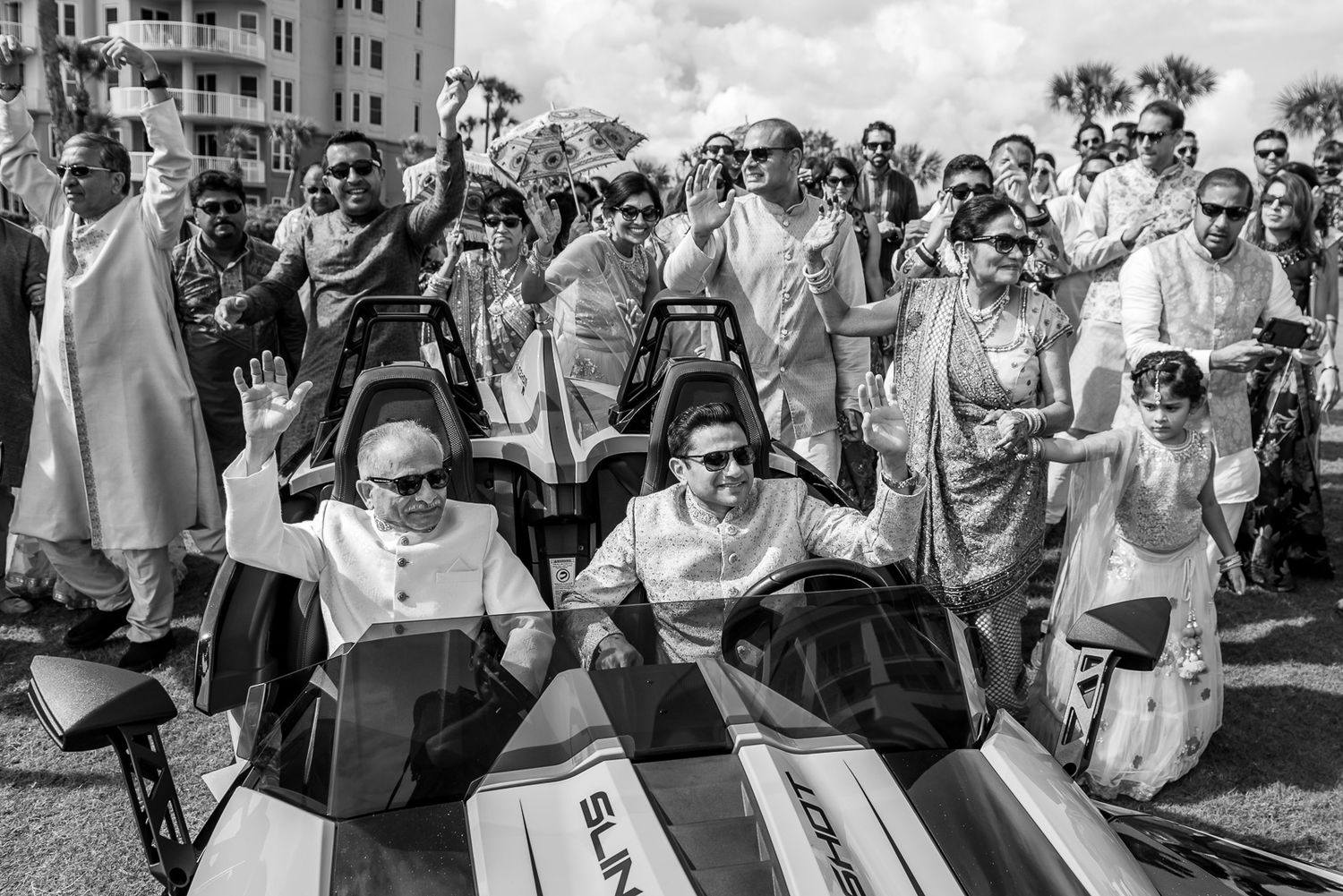 Black and white photo of wedding party riding jet skis in formal attire.