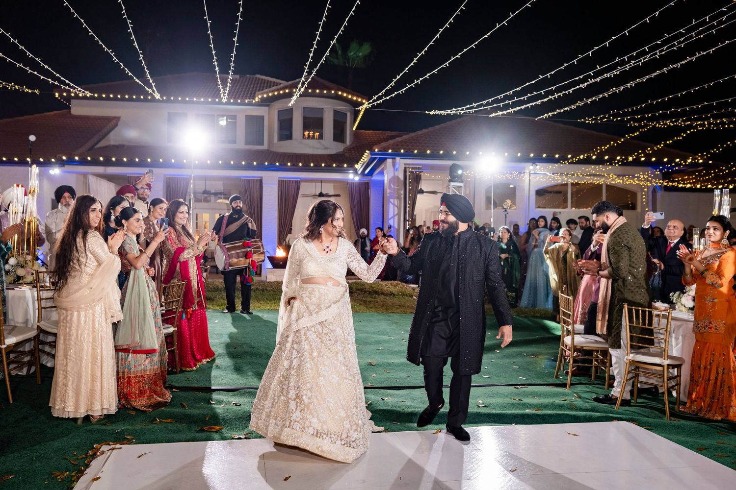 Evening wedding reception with string lights and guests gathered on an outdoor dance floor.