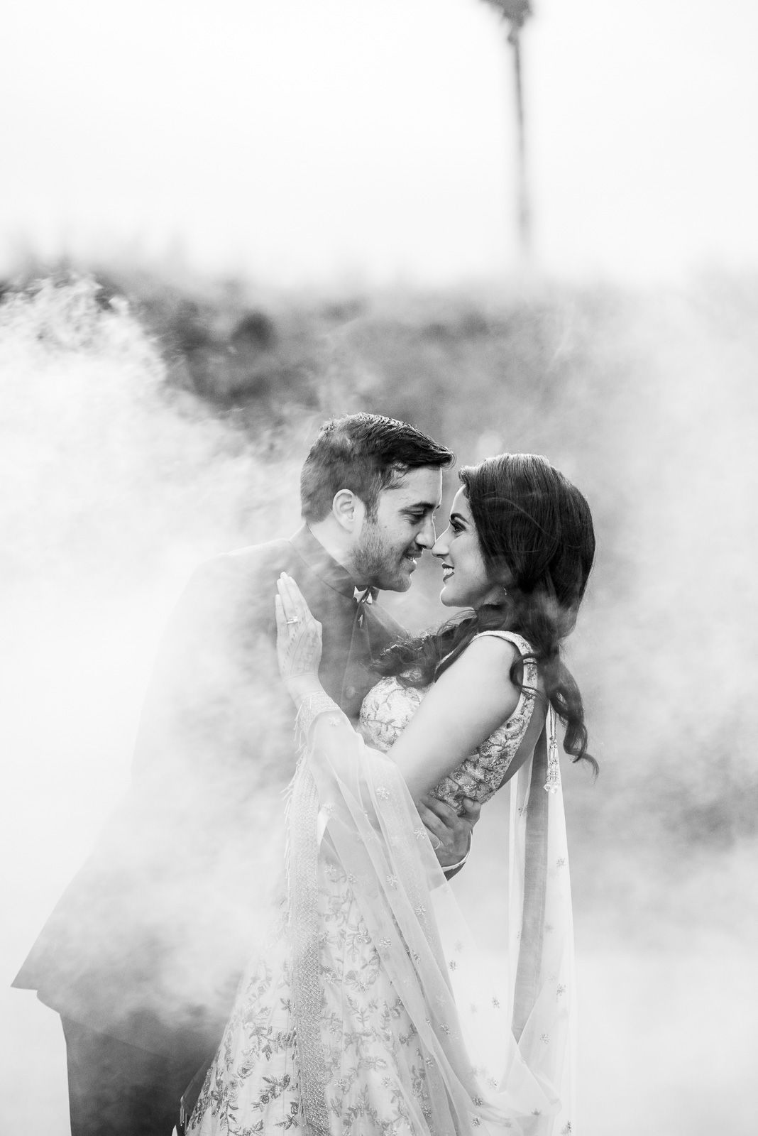 Artistic black and white wedding portrait with dramatic smoke effect.