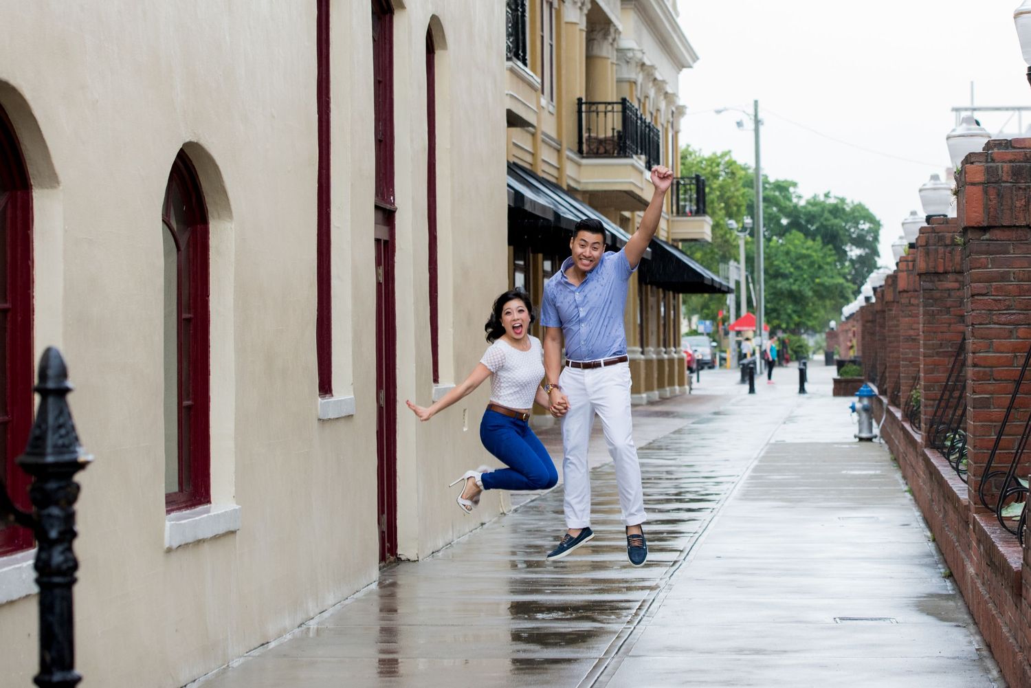 Couple posing playfully on a wet cobblestone street in a historic district.