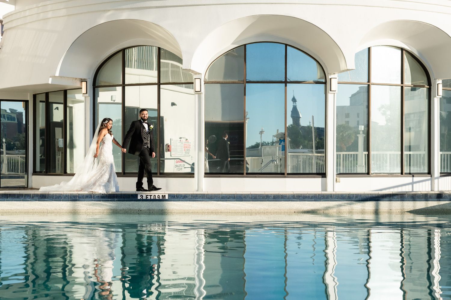 Modern archways and reflective pool create an elegant wedding venue setting.