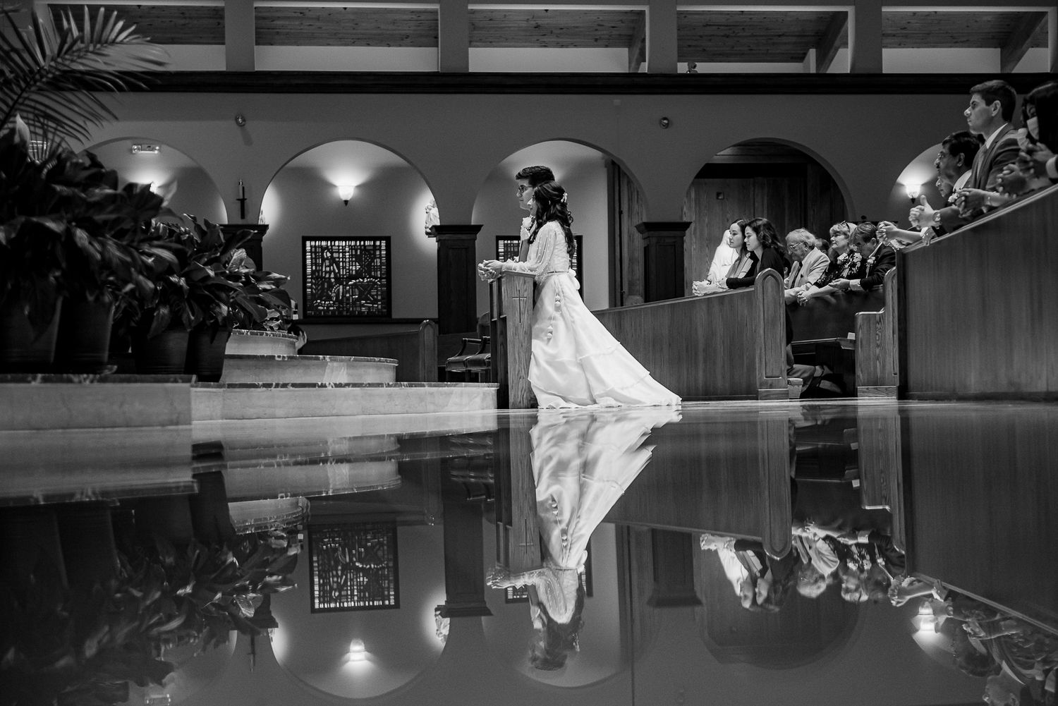 Artistic black and white wedding photo with reflection on polished floor in elegant venue.