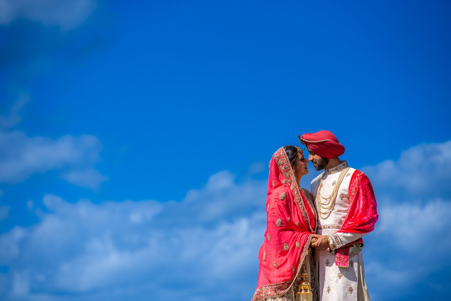 Traditional cultural wedding attire against a bright blue sky backdrop.