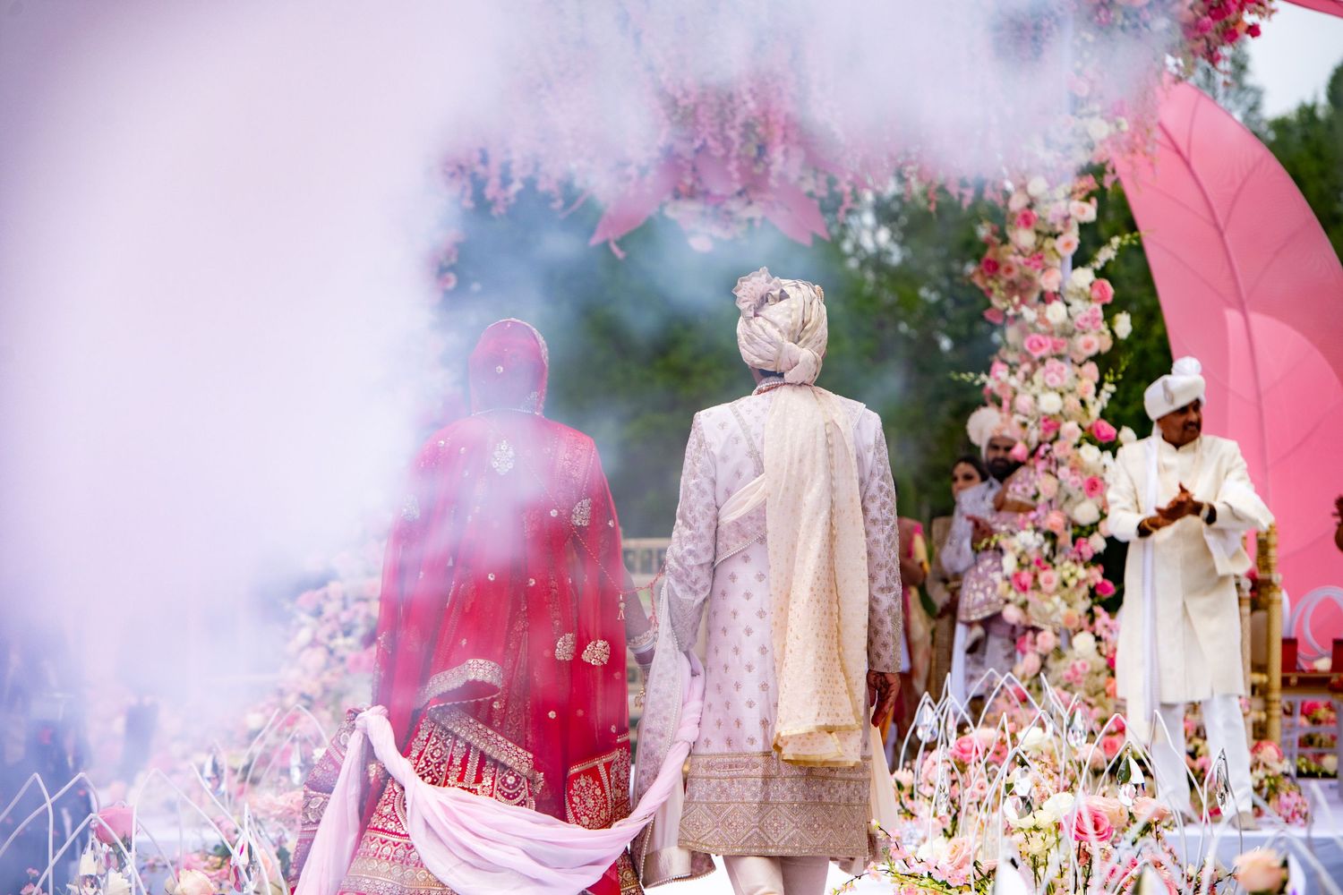 Dreamy wedding scene with pink smoke effects and floral decorations creating ethereal atmosphere.