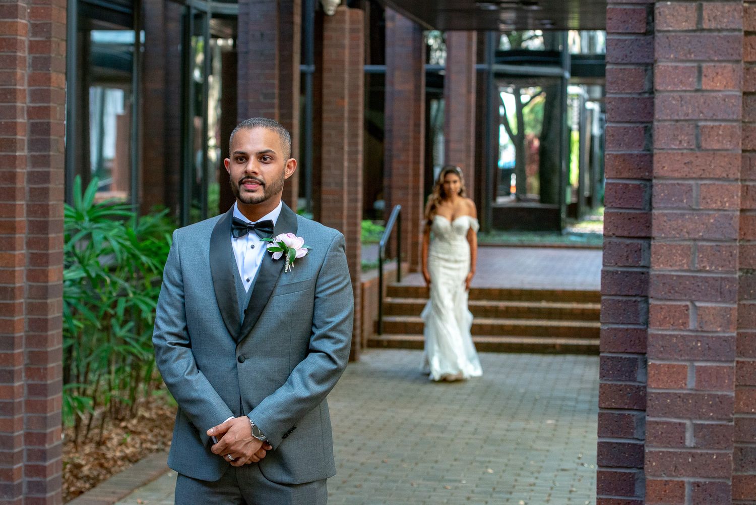 Wedding first look moment captured between columns of brick building.