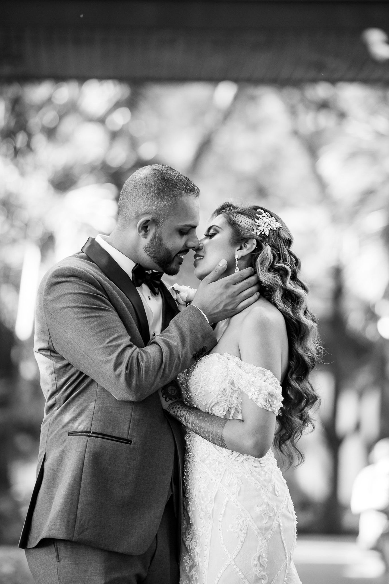 Intimate black and white wedding portrait of a couple sharing a romantic moment outdoors.