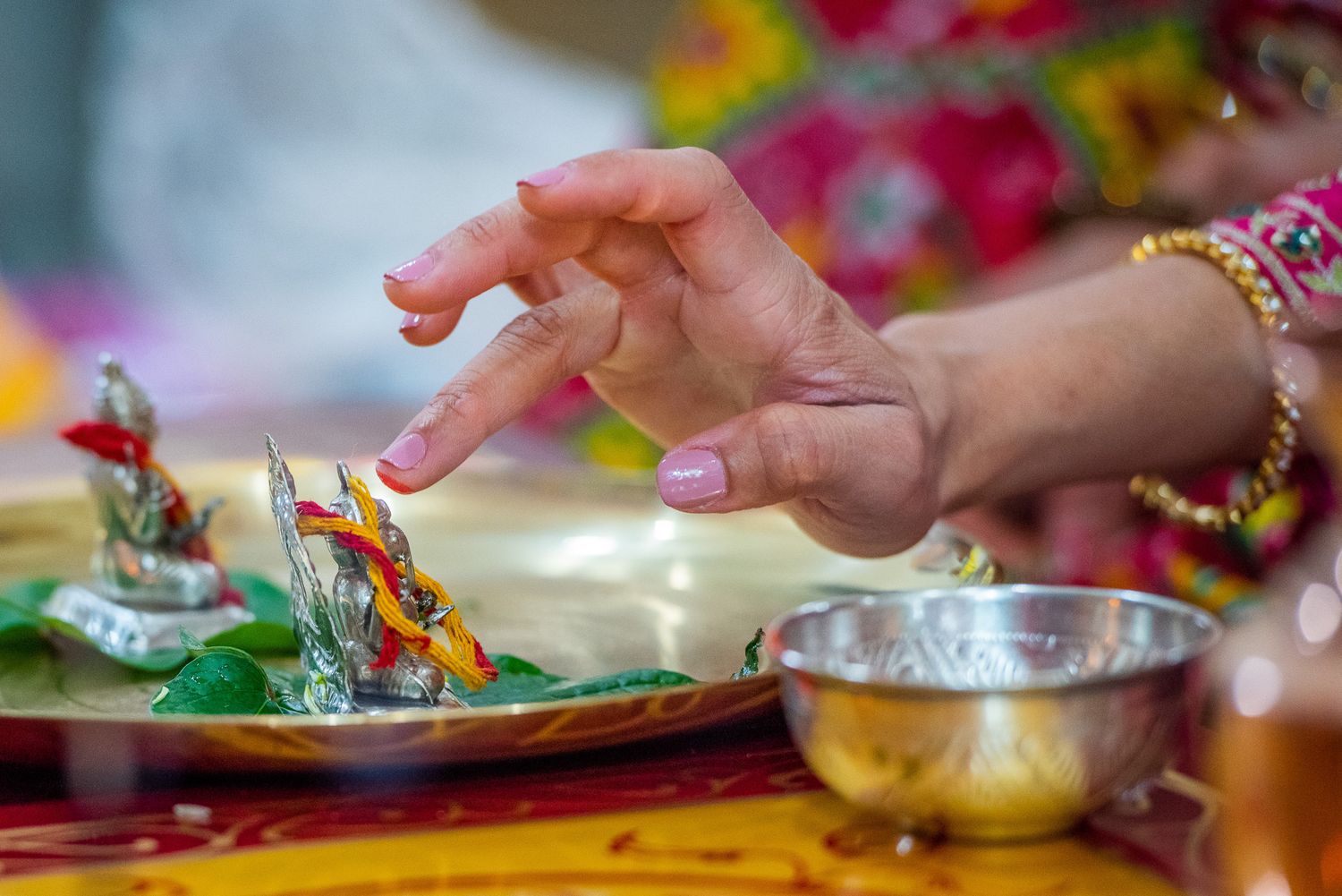 Hand adorned with traditional Indian jewelry reaching for food during a wedding celebration.