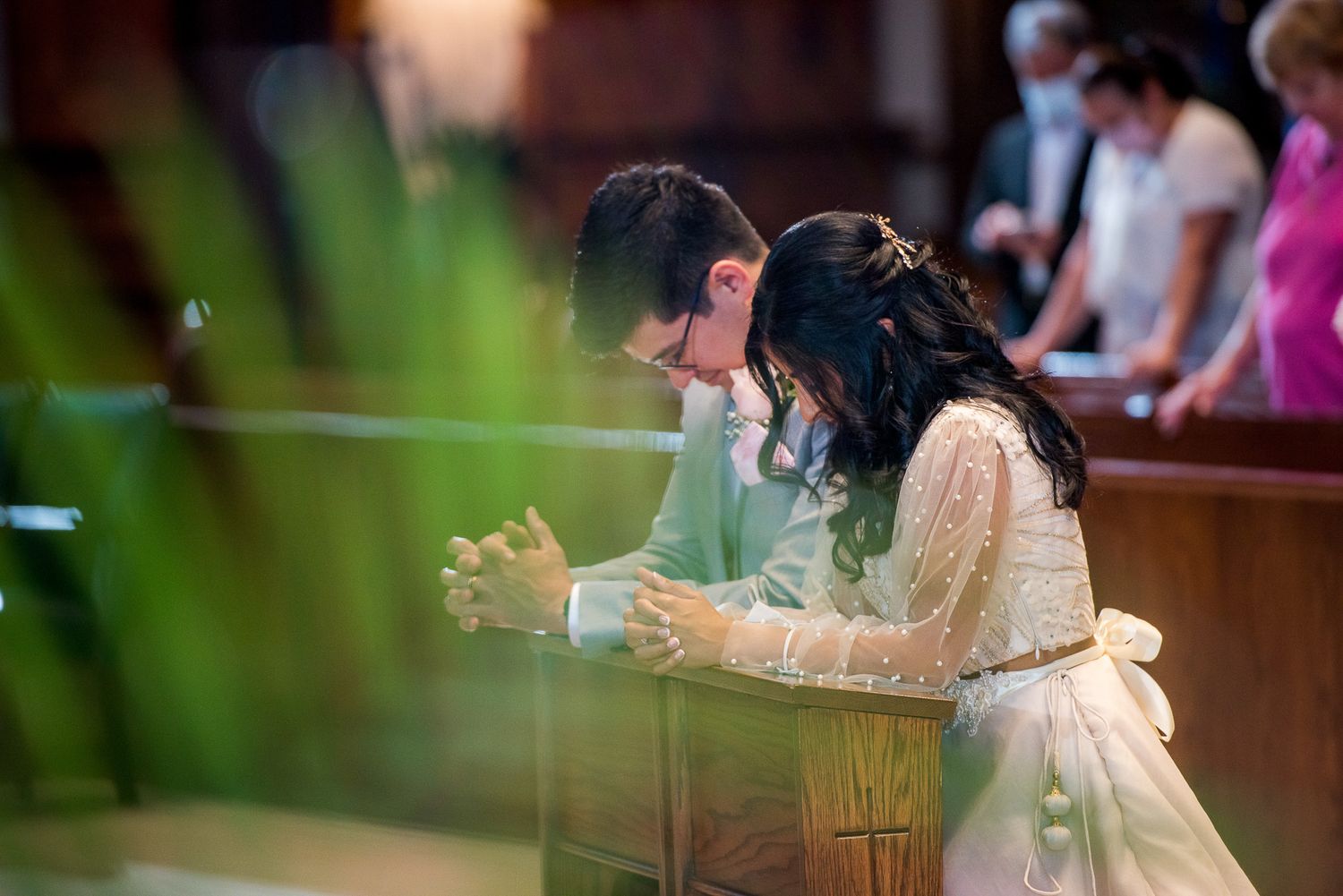 Wedding ceremony moment showing couple praying together in traditional church setting.