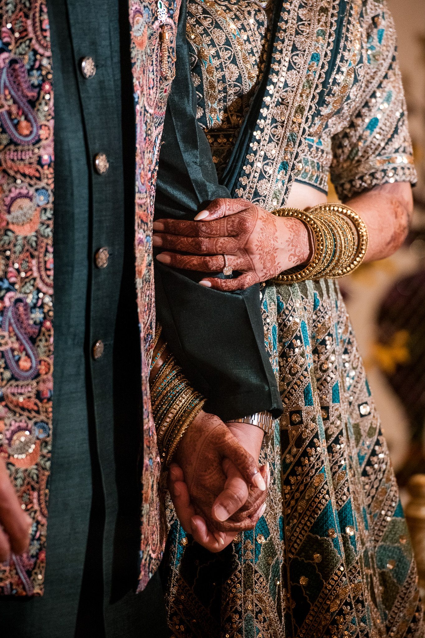 Close-up of traditional Indian wedding attire showing detailed embroidery and gold bangles.
