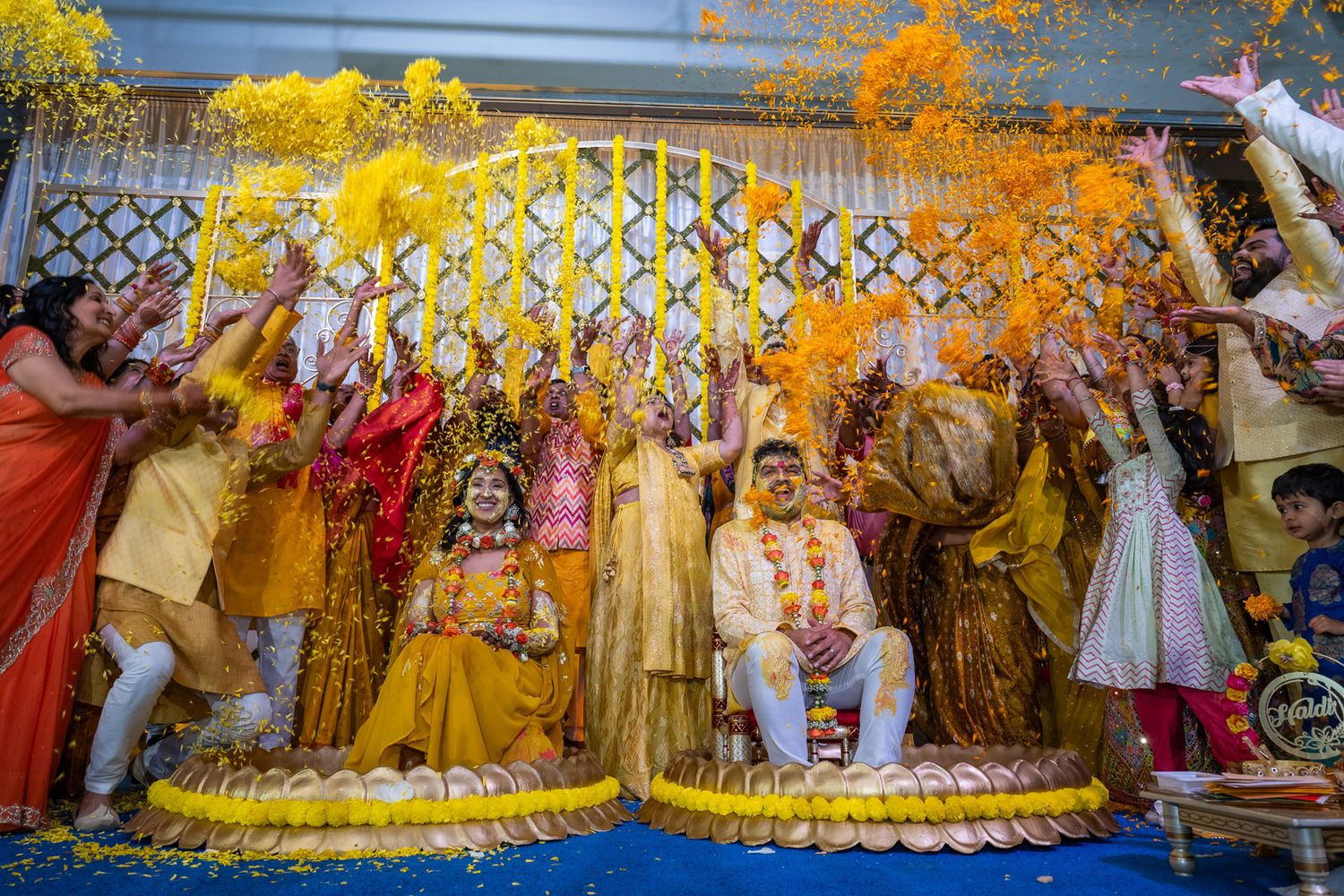 Festive Indian wedding celebration with yellow powder being thrown during traditional ceremony.