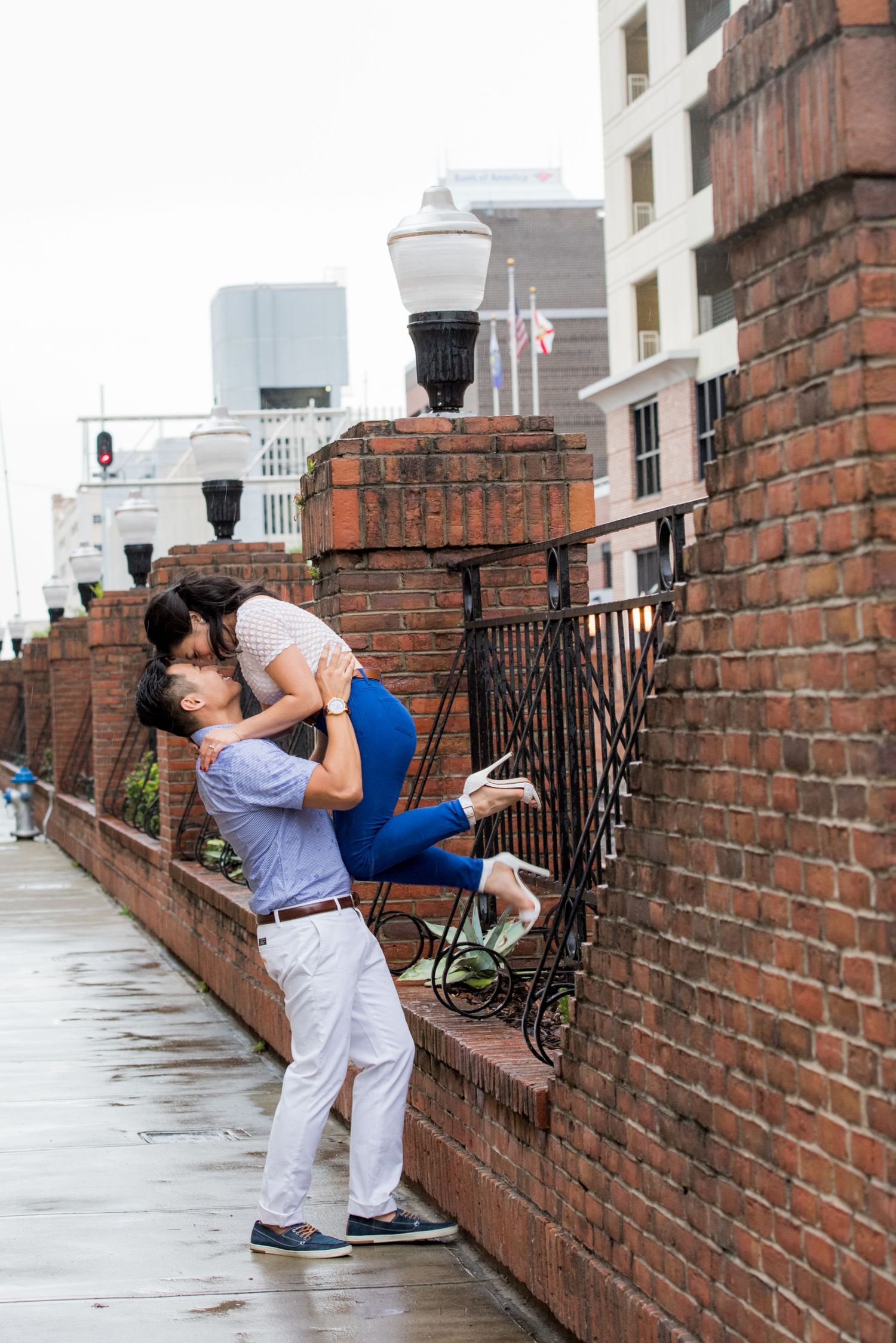 Couple sharing a romantic moment against a brick wall in an urban setting.