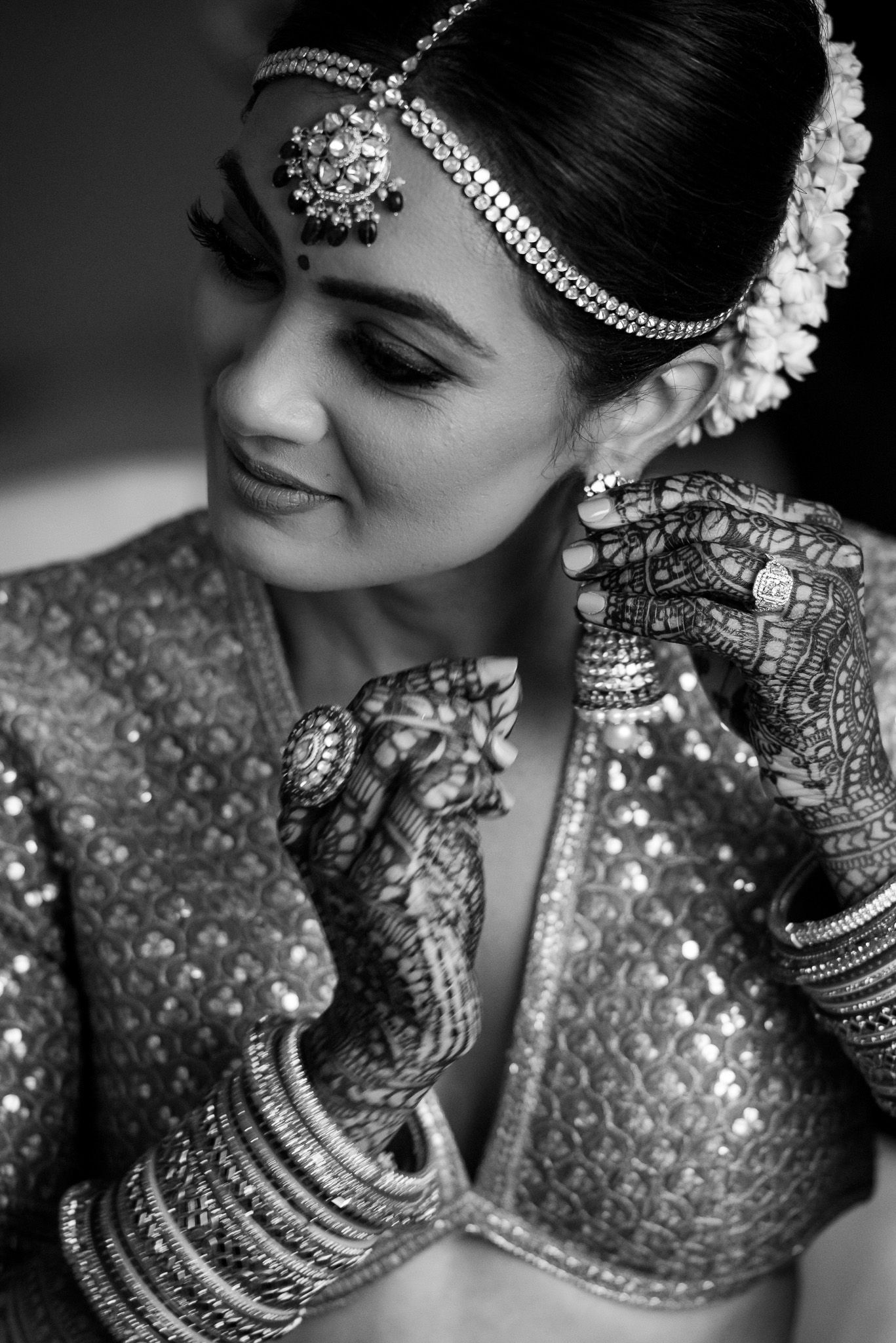 Close-up detail of traditional Indian bridal jewelry and henna decorated hands.