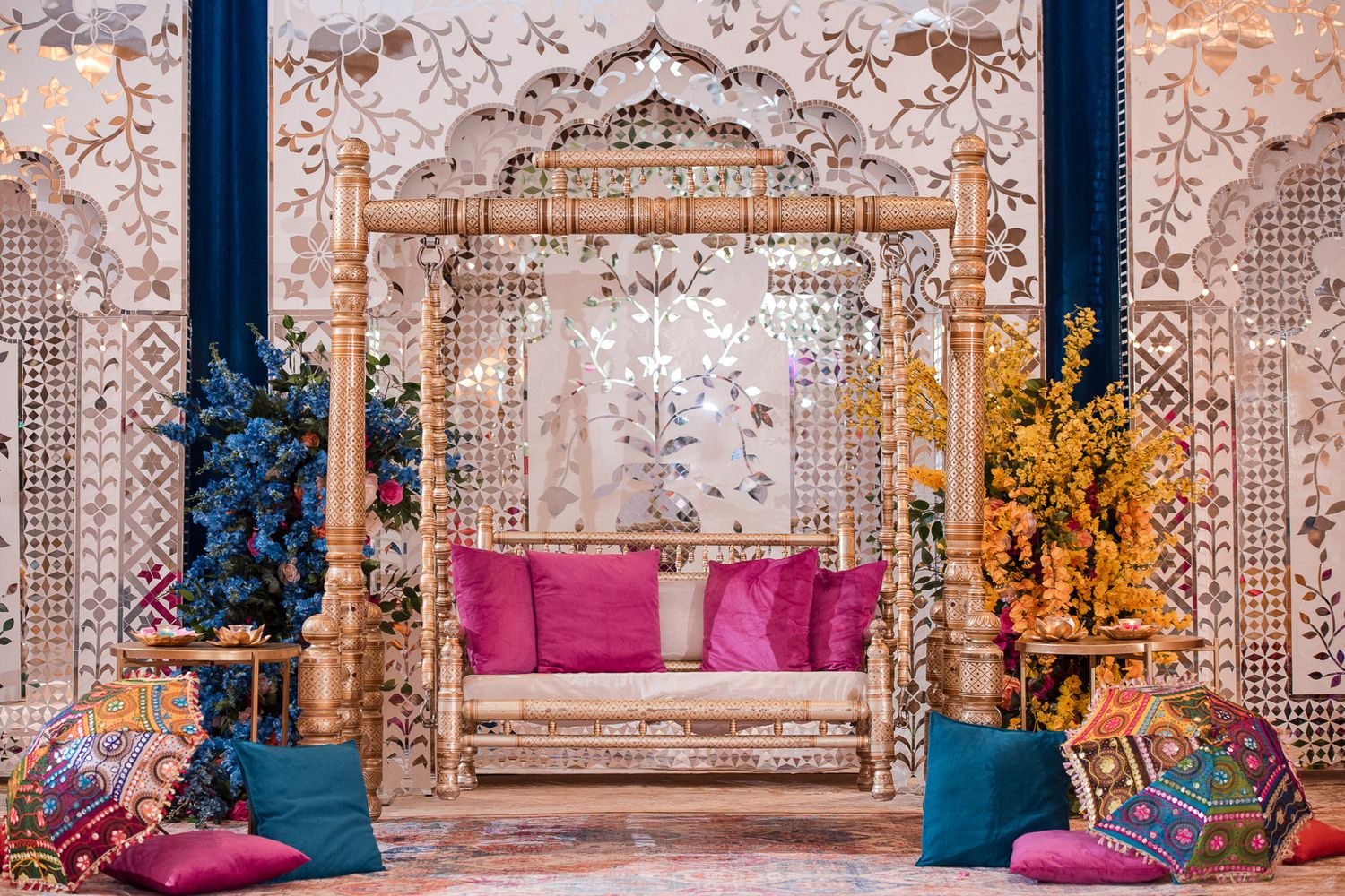 Elegant wedding stage setup with ornate patterns, magenta cushions and gold accents.
